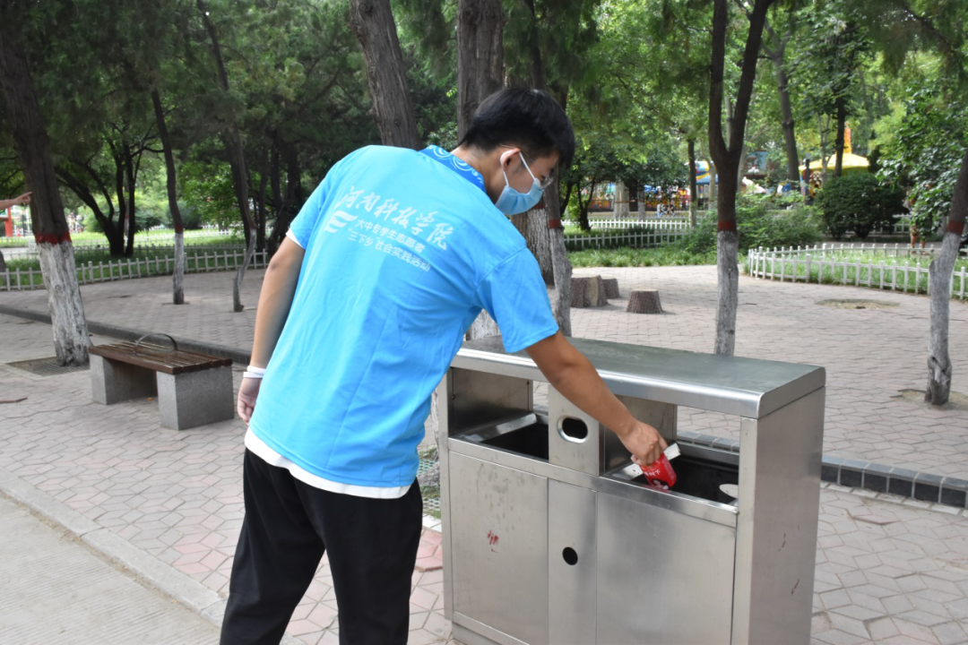 实践队员正将拾捡的垃圾丢进垃圾桶